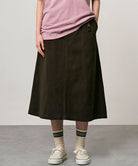 Model wearing a coffee colored Gramicci Venture Skirt and a pink shirt on a light-tone background.
