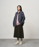 Model wearing a coffee colored Gramicci Venture Skirt and a blue plaid shirt on a light-tone background.