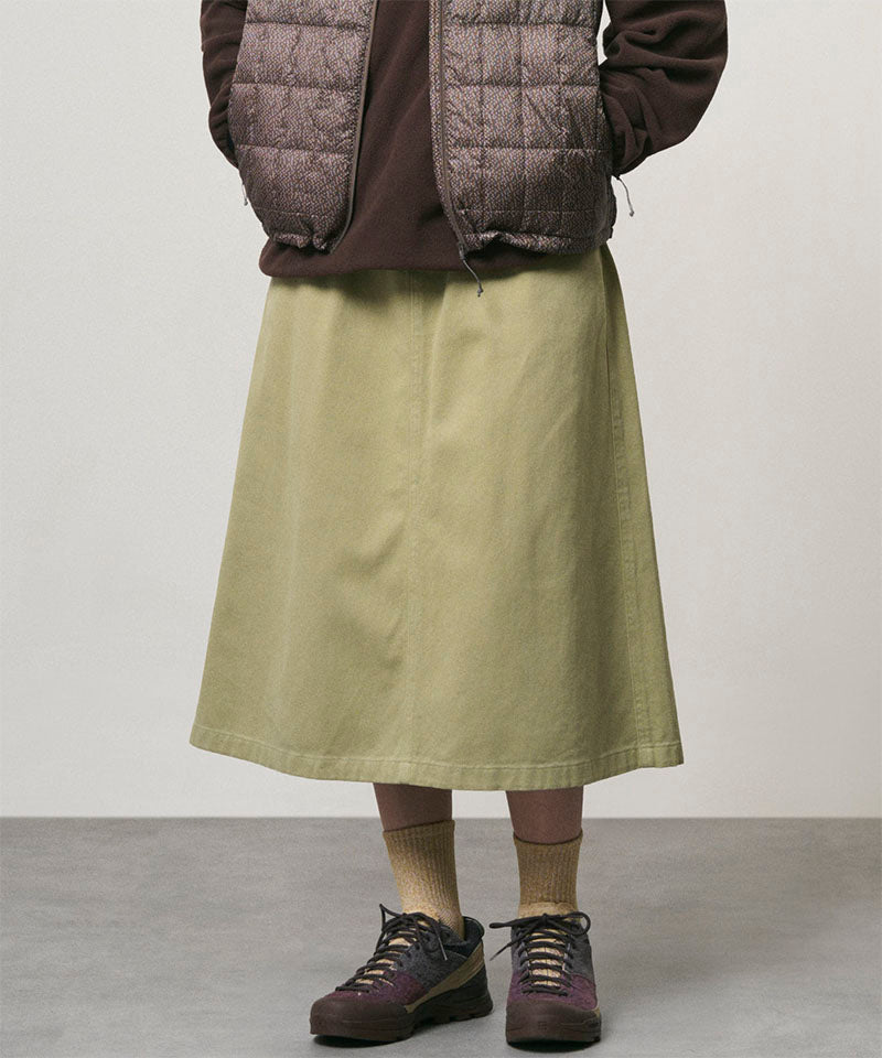 Model wearing a elm colored Gramicci Venture Skirt and a brown vest on a light-tone background.