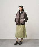 Model wearing a elm colored Gramicci Venture Skirt and a brown vest on a light-tone background.