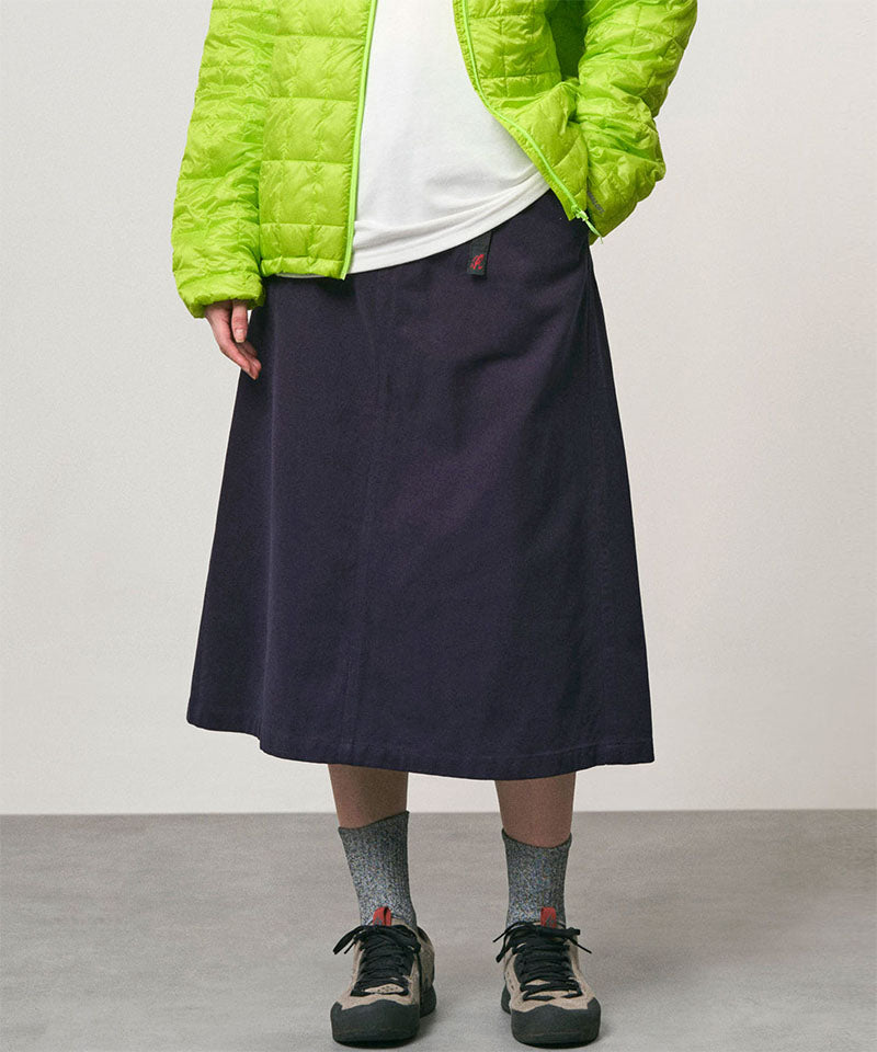 Model wearing a ink colored Gramicci Venture Skirt and a bright green jacket on a light-tone background.
