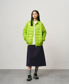 Model wearing a ink colored Gramicci Venture Skirt and a bright green jacket on a light-tone background.