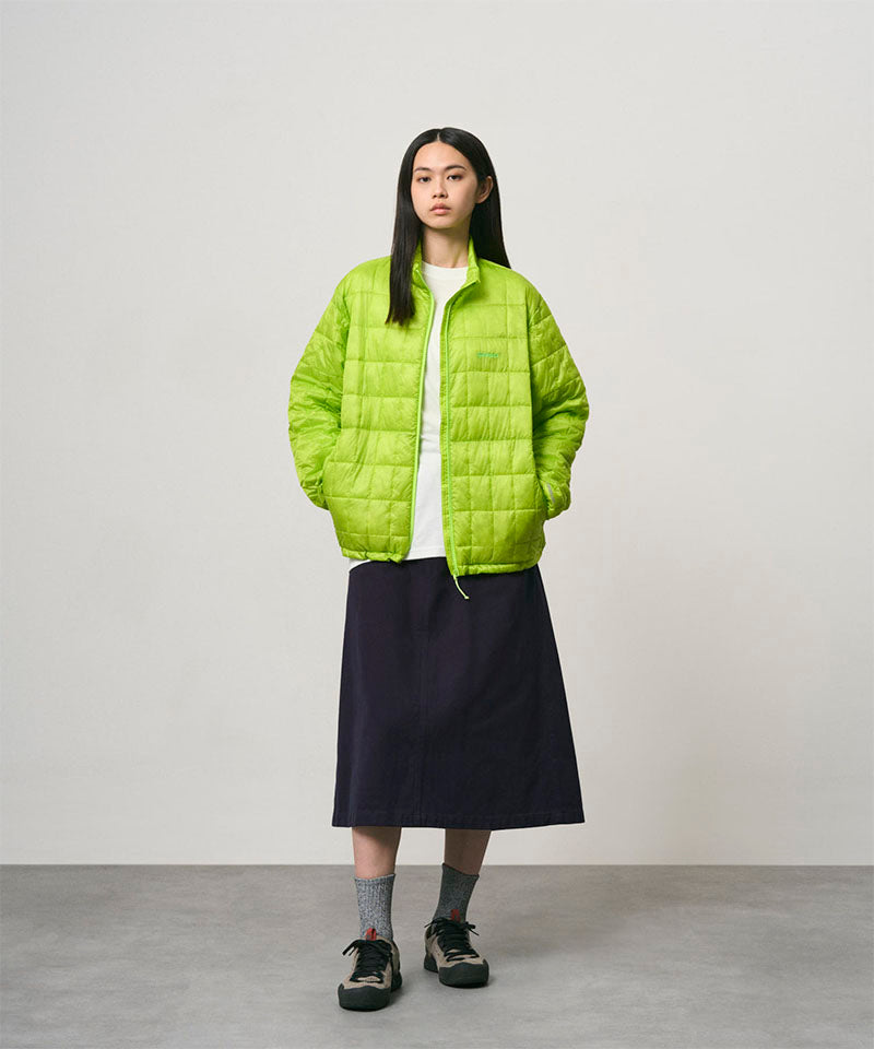Model wearing a ink colored Gramicci Venture Skirt and a bright green jacket on a light-tone background.