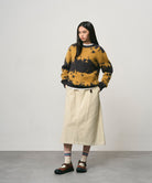 Model wearing a sand colored Gramicci Venture Skirt and a yellow and black tie-die sweater on a light-tone background.