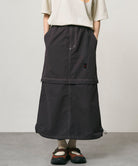 Model wearing a black women's Gramicci WR Convertible Skirt and a creme colored shirt on a light-tone background.
