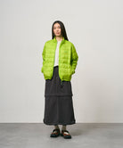 Model wearing a black women's Gramicci WR Convertible Skirt and a bright green jacket on a light-tone background.