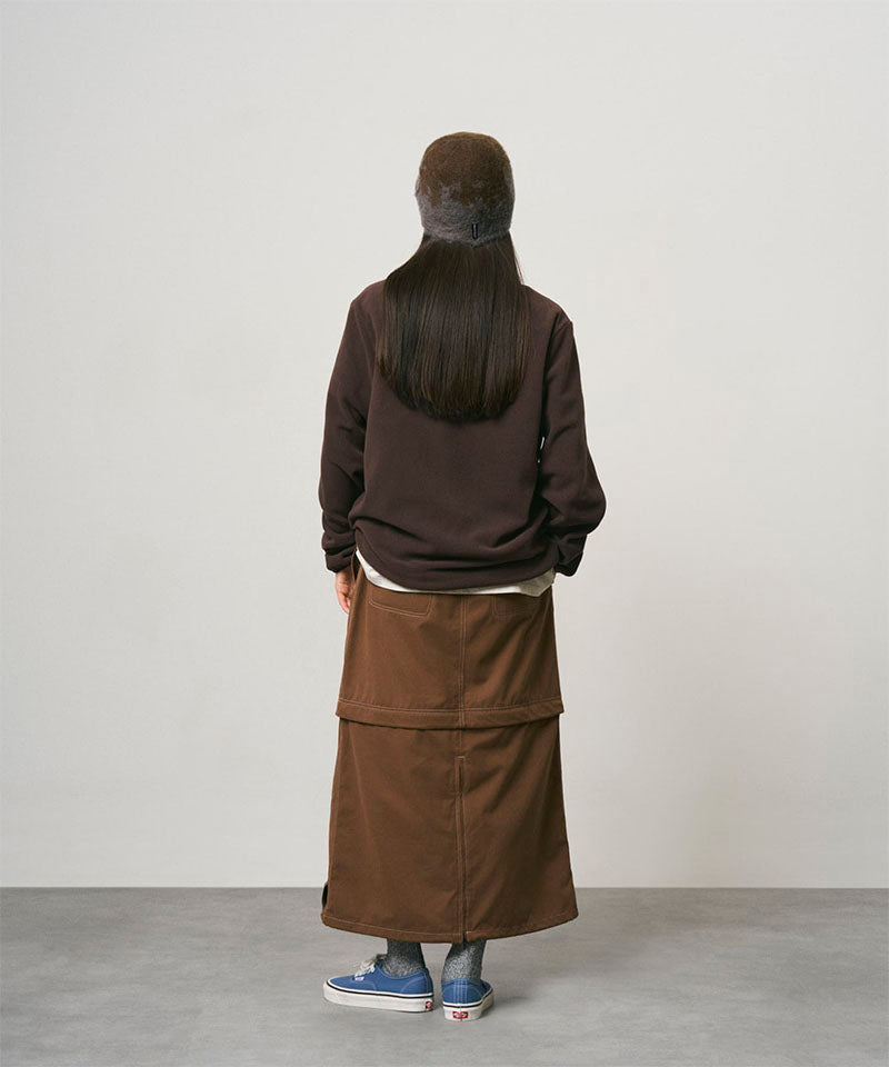 Back view of a model wearing a deep brown women's Gramicci WR Convertible Skirt and a dark brown shirt on a light-tone background.