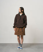 Model wearing a deep brown women's Gramicci WR Convertible Skirt and a dark brown jacket on a light-tone background.