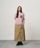 Model wearing a khaki colored women's Gramicci WR Convertible Skirt and a dusty pink shirt on a light-tone background.
