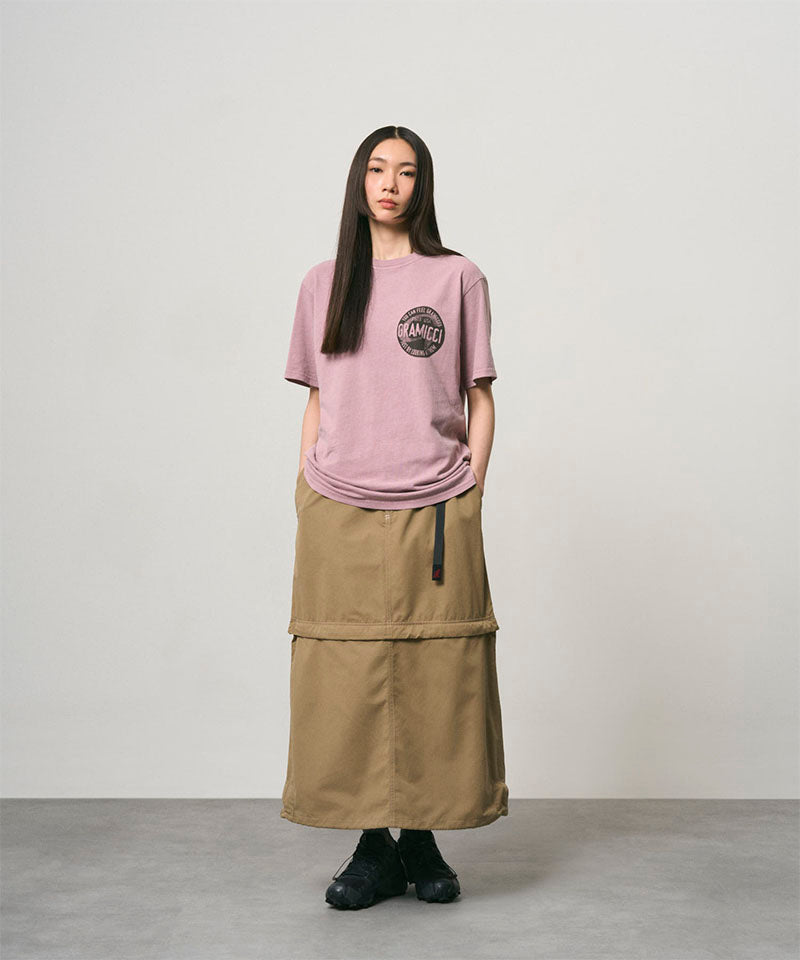 Model wearing a khaki colored women's Gramicci WR Convertible Skirt and a dusty pink shirt on a light-tone background.