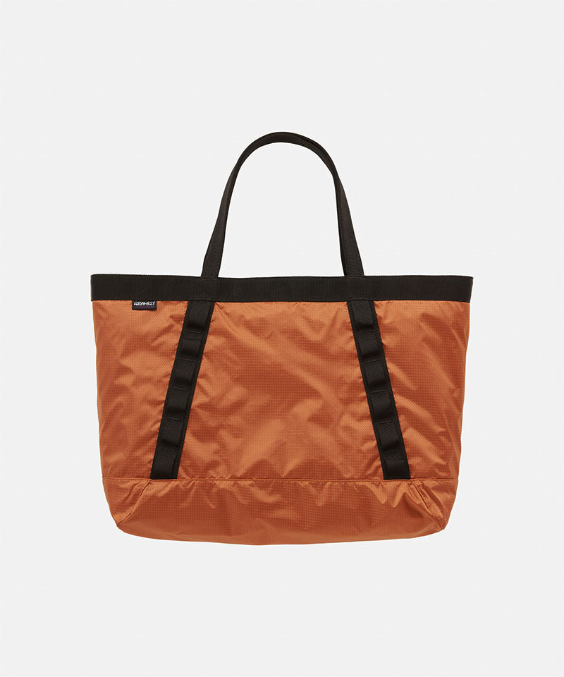Orange Gramicci Trail Tote bag with black straps on a light tone background