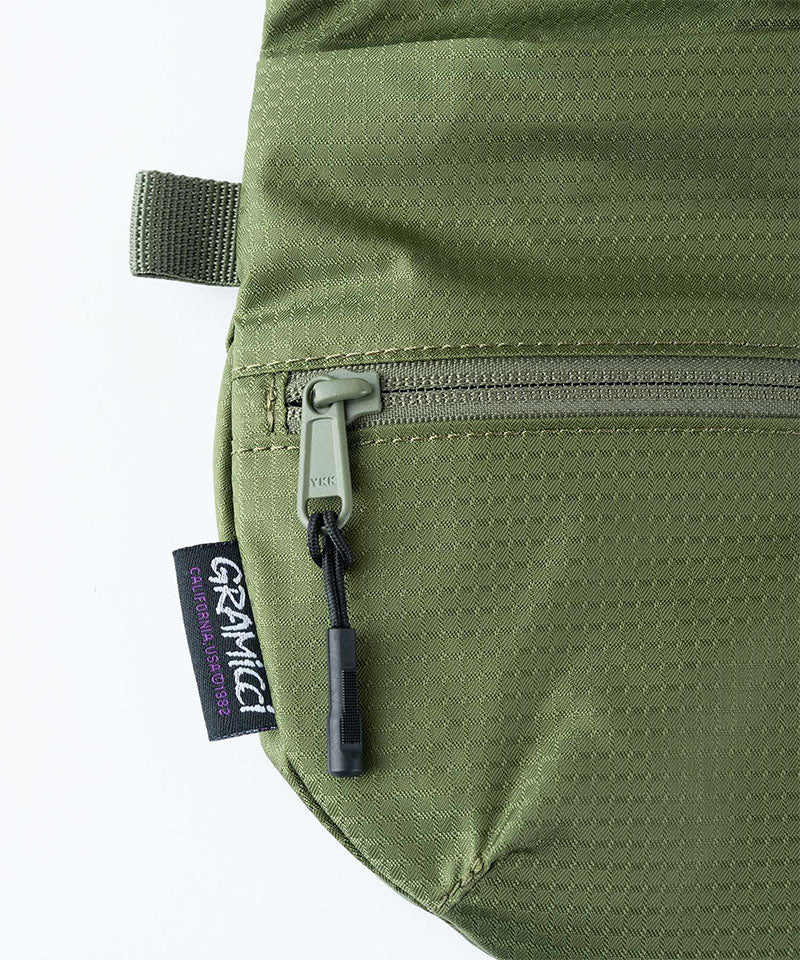 Close-up of Gramicci Field Sacoche bag in the color olive against a light-tone background.