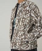 Model wearing a Gramicci grey reed camouflage Taos Canvas Jacket against a light-tone background.