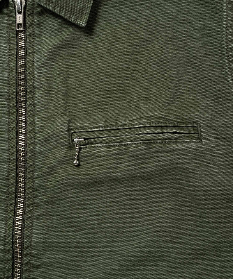 Close-up of a moss green Gramicci Taos Canvas Jacket on a light-tone background.