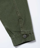 Close-up of the cuff and sleeve on a moss green Gramicci Taos Canvas Jacket showing branded buttons on a light-tone background.