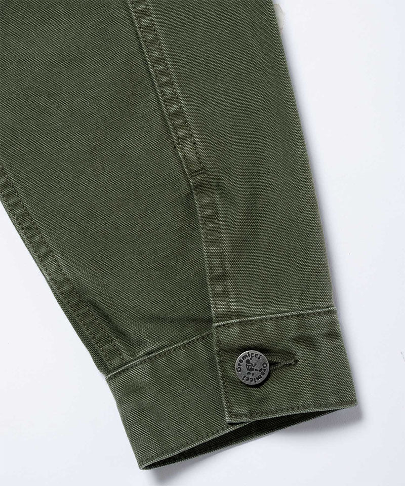 Close-up of the cuff and sleeve on a moss green Gramicci Taos Canvas Jacket showing branded buttons on a light-tone background.