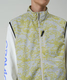 Person wearing a light-colored jacket with a subtle pattern on a plain background