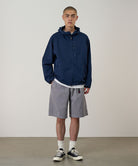 Model wearing a Gramicci Natural Dyed Jam Short in the color grey and a blue hoodie on a light-tone background.
