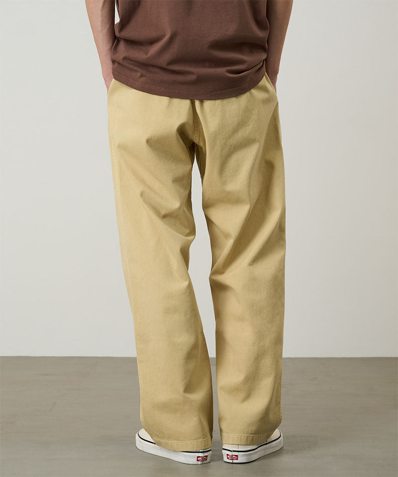 Back view of a model wearing a Natural Dyed Gramicci Pant Straight Fit in the color chino on a light-tone background.
