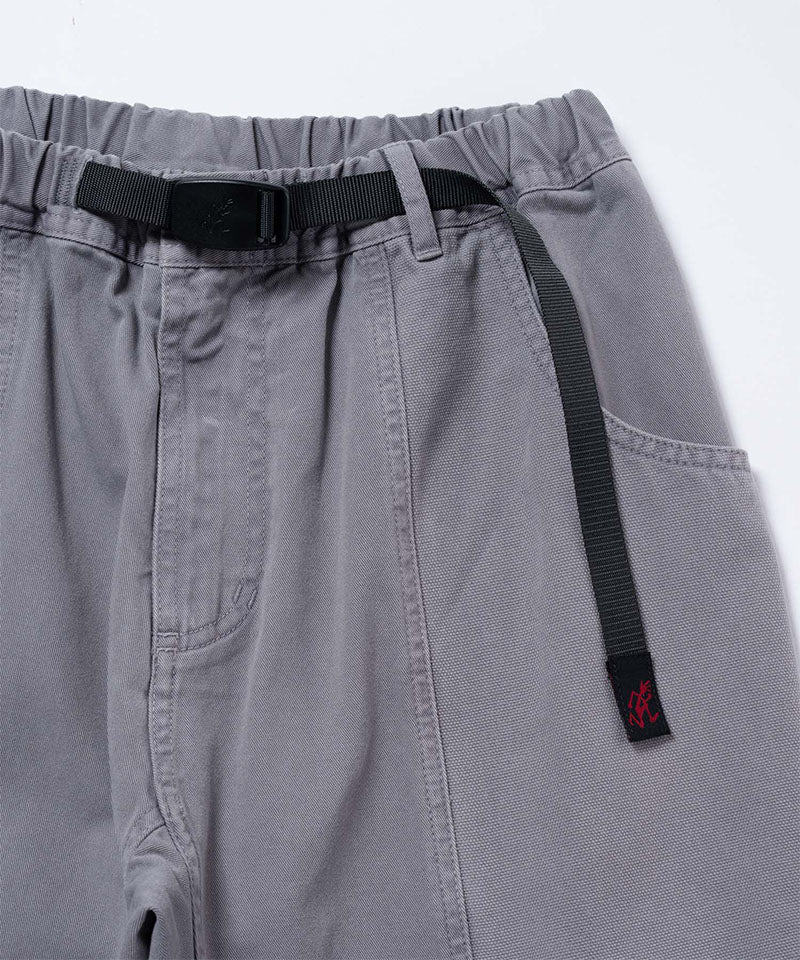 Close-up of natural dyed grey Gramicci Gadget Pants with a black belt on a light-tone background.
