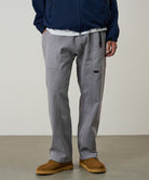 Model wearing a Gramicci natural dyed grey Gadget Pants against a light-tone background.
