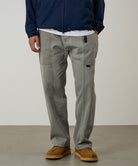 Model wearing a Gramicci natural dyed olive Gadget Pants against a light-tone background.
