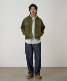 Model wearing navy Japanese Chambray Rock Slide Pant and a moss green jacket on a light-tone background.