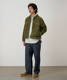 Model wearing navy Japanese Chambray Rock Slide Pant and a moss green jacket on a light-tone background.