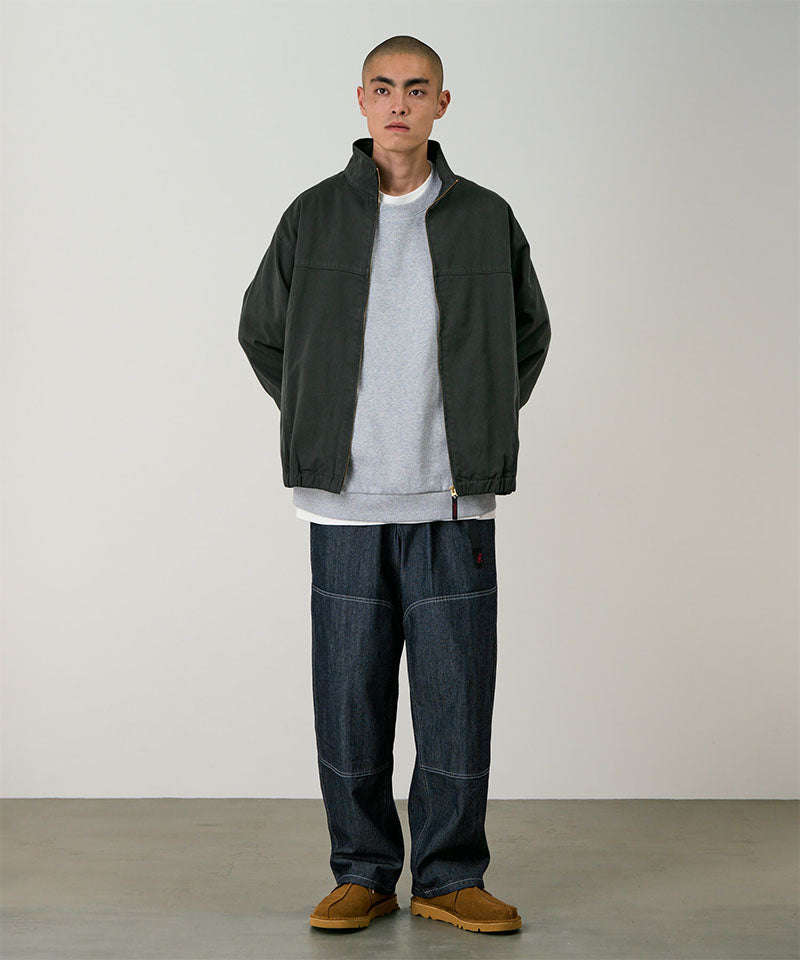 Model wearing the Gramicci Japanese Chambray Double Knee pant in navy and a dark green jacket on a light tone background.
