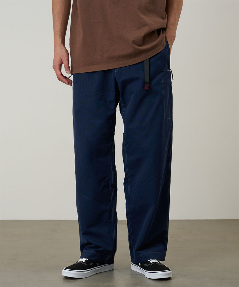 Model wearing dark navy Gramicci Milton Pants and a brown shirt on a light-tone background.