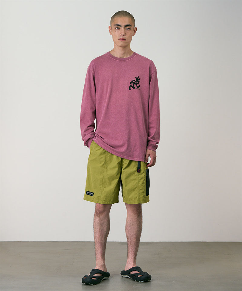 Person wearing a red long-sleeve shirt and green shorts against a plain background