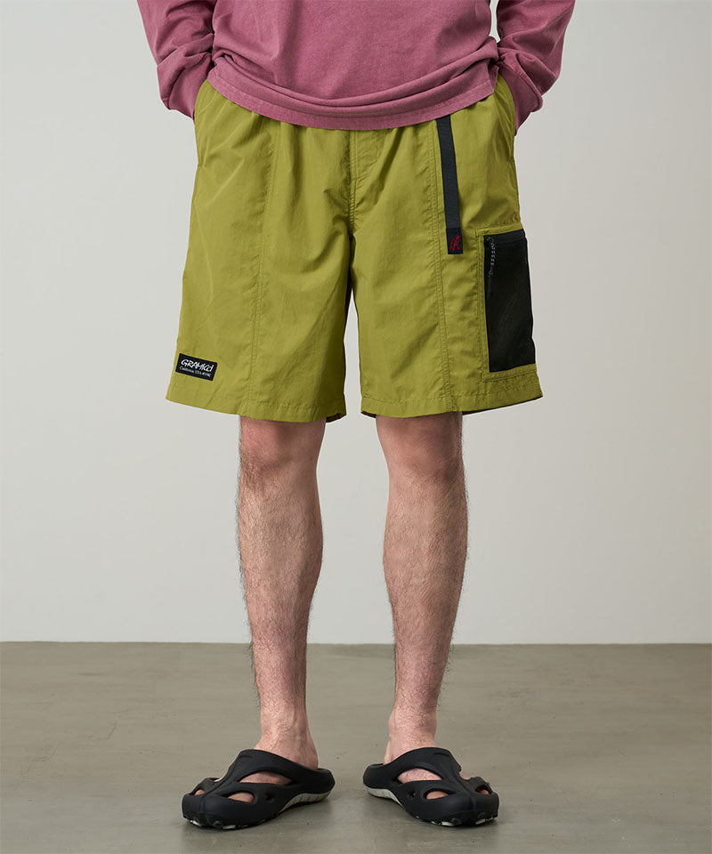 Person wearing green shorts with a visible brand label on a plain background