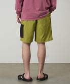 Person wearing green shorts and a red shirt on a plain background