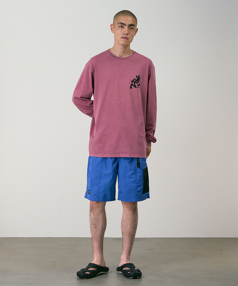 Person wearing a maroon long-sleeve shirt and blue shorts against a plain background