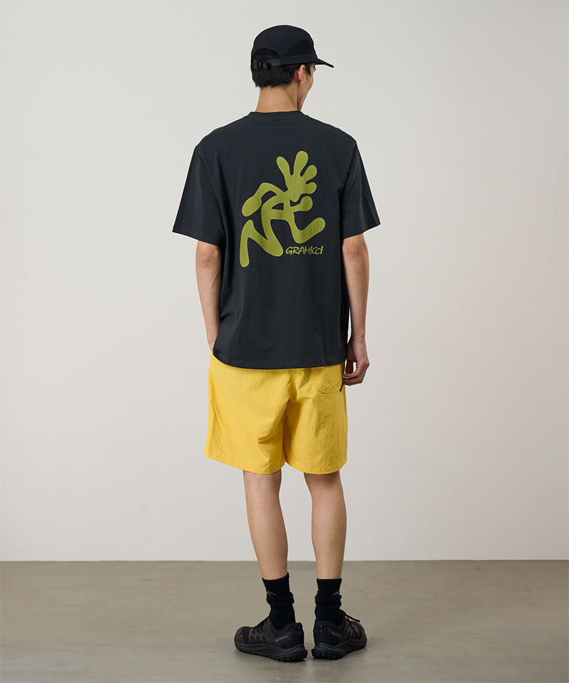 Person wearing a black t-shirt with green graphics and yellow shorts on a plain background