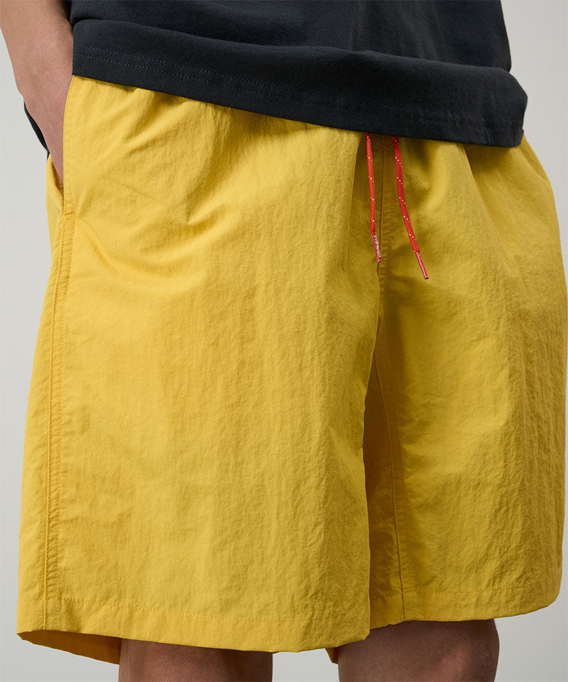 Yellow shorts with red drawstring on a plain background