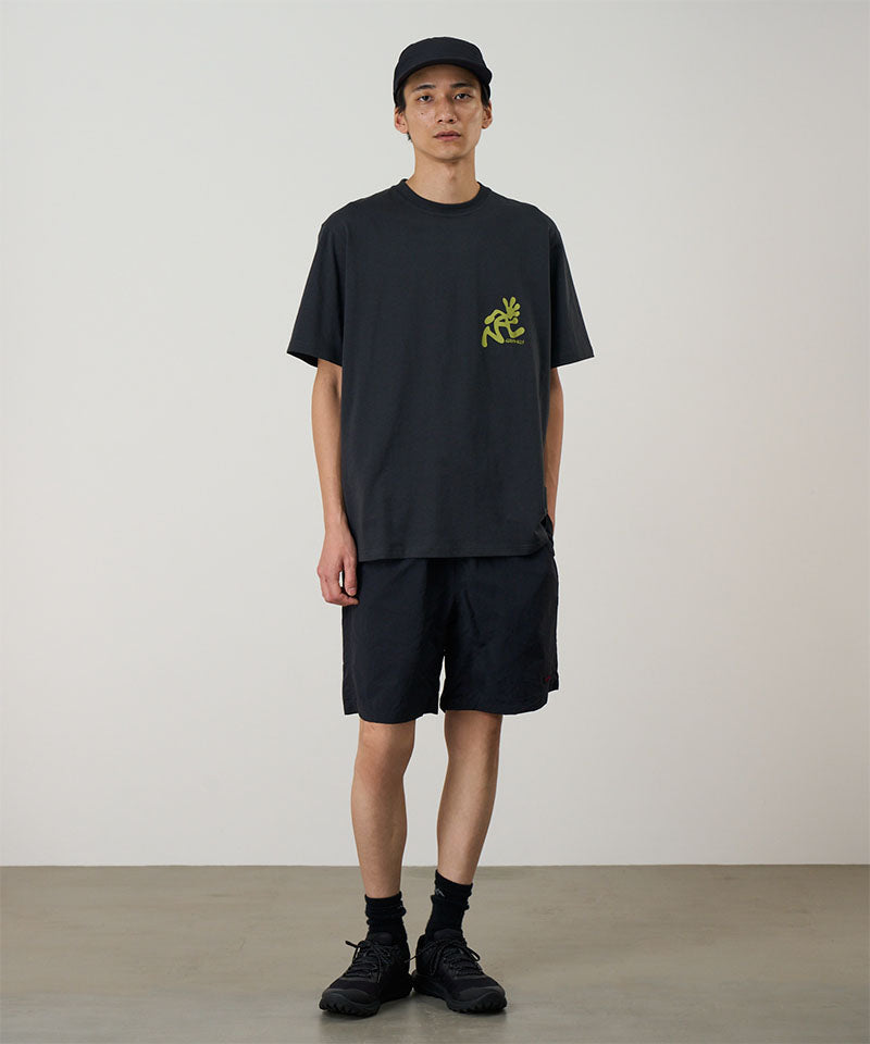 Person wearing a black t-shirt with a logo and black shorts on a plain background