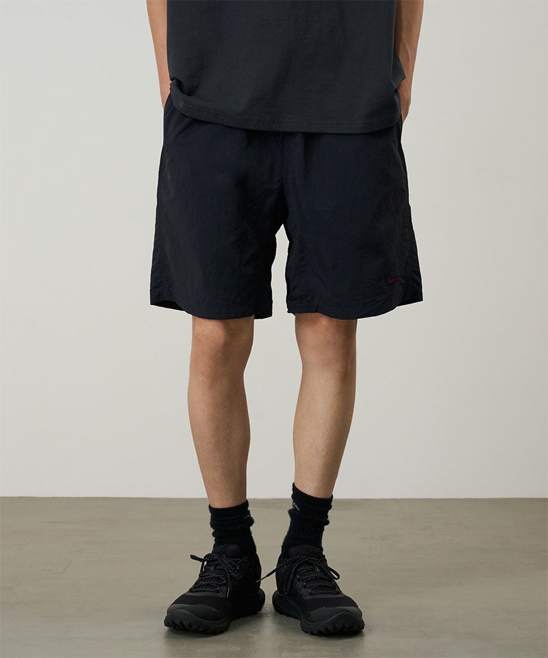 Person wearing black shorts and shoes on a plain background