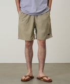 Person wearing khaki shorts and sandals on a plain background