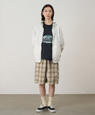 Model wearing the Gramicci Beach Hoodie Jacket in stone with tan plaid shorts on a light tone background.