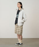 Side view of a model wearing the Gramicci Beach Hoodie Jacket in stone with tan plaid shorts on a light tone background.