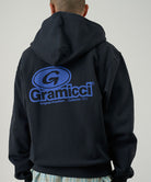 Person wearing a black hoodie with a blue Gramicci logo on the back against a plain background