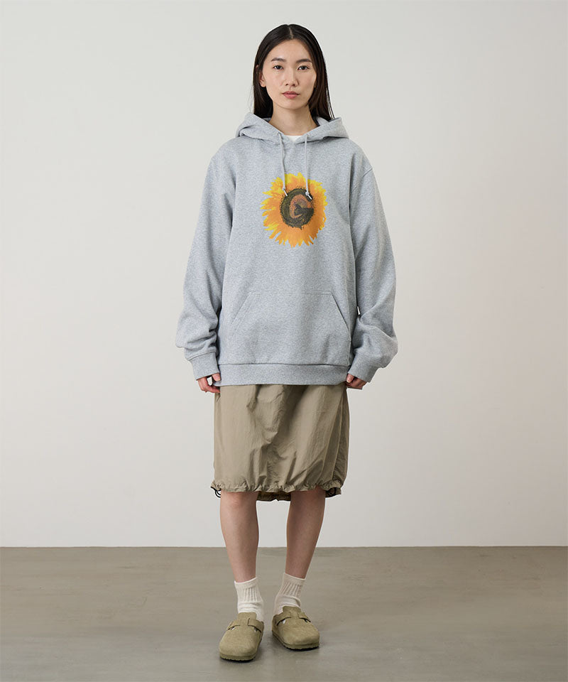 Person wearing a gray hoodie with a sunflower design on a plain background
