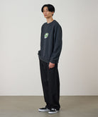 Person wearing a dark gray sweatshirt with a logo and black pants against a plain background