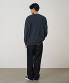 Person wearing a dark gray sweatshirt and black pants against a plain background