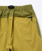 Olive yellow pants with green accents on a light tone background