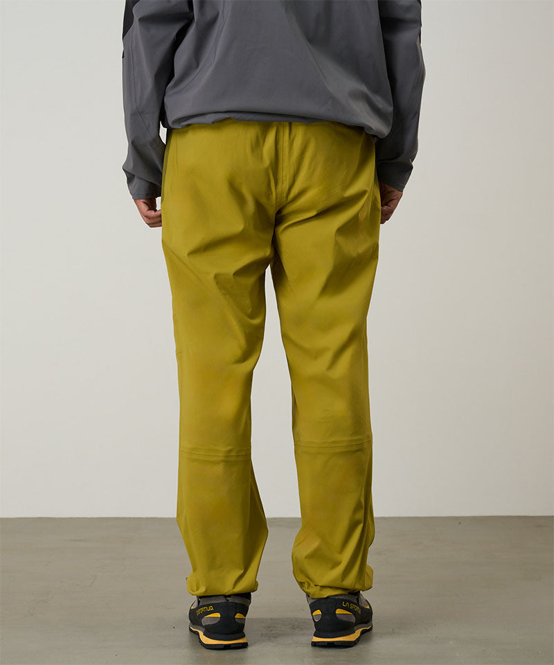 Person wearing yellow olive pants and a gray jacket on a light tone background
