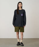 Model wearing a vintage black Gramicci Equipped For Dirt L/S Tee with a a Gramicci gear graphic graphic and olive shorts on a light tone background.