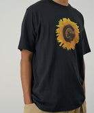 Model wearing a Gramicci vintage black G-Flower Tee with sunflower graphic against a light tone background.