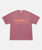 Gramicci red pigment Freedom Tee Pigment Dyed with mango colored graphic against a light tone background.